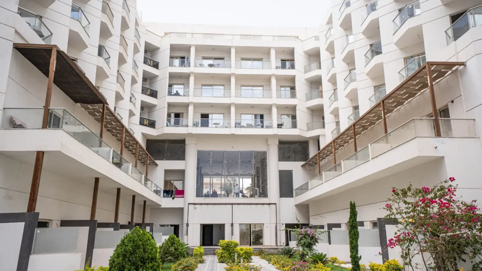 Vista dal giardino interno con viale lastricato e aiuole verso la facciata interna del complesso Scandic Beach Resort di Hurghada, Egitto – Vivere Hurghada